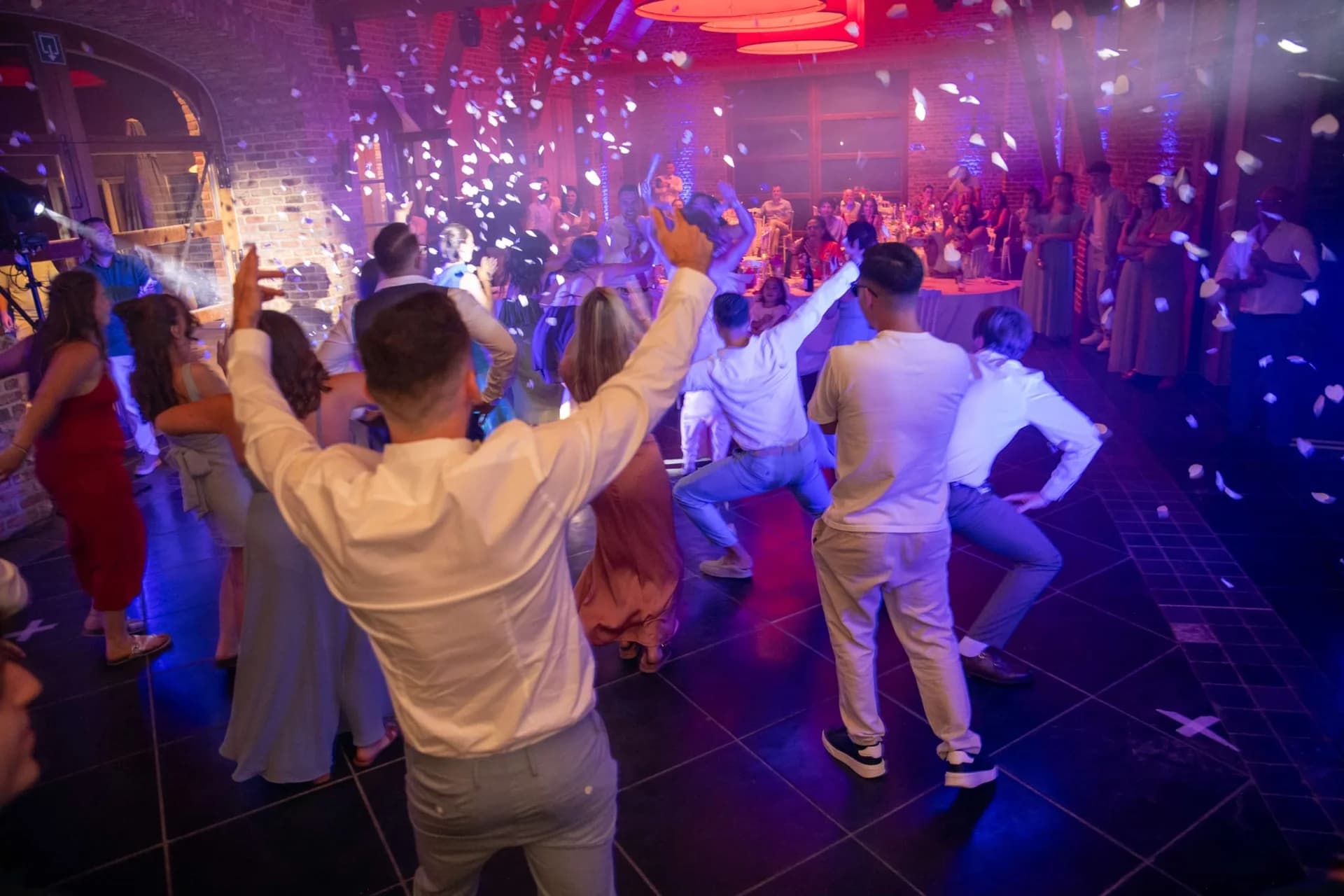 Les invités dansent sous les confettis et les lumières colorées lors d'une soirée de mariage